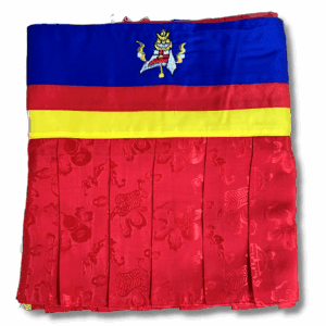 Red ruffled Tibetan shrine banner with blue, yellow, and red bands at the top and an embroidered protective symbol, made from brocade fabric for hanging in a meditation or altar space.