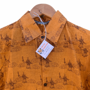 A burnt orange colored shirt with short sleeves, featuring traditional Tibetan Opera prints and wooden buttons, displayed on a hanger.
