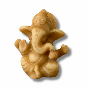 A small seated Ganesha statue in warm red-brown tones, with an elephant head, large ears, and rounded belly, holding objects in his hands while sitting cross-legged on a carved base against a neutral background.