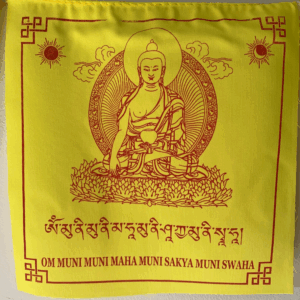A yellow prayer flag featuring an illustration of Buddha Shakyamuni and the mantra in Tibetan script and English letters, printed in Nepal.