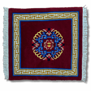 Handwoven Tibetan meditation carpet in deep red with geometric mandala centre, decorative border, and white fringe edges.