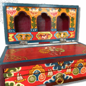 A folding wooden altar box with colorful hand-painted designs, featuring compartments and a brass latch.