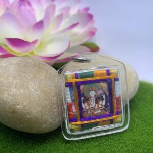 A protective amulet featuring a colorful depiction of the Buddha and other spiritual figures encased in a clear plastic cover, with a floral pattern on the border.