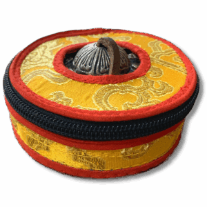 Round Tibetan meditation cymbals case made from yellow brocade with red trim, featuring a central metal button and zip closure for protecting tingsha bells.