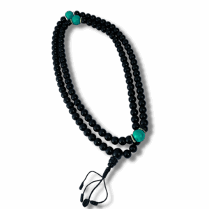A black obsidian stone mala with turquoise howlite counters, displayed against a dark background.