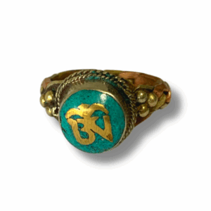 Multiple turquoise howlite Mani mantra rings arranged on a light background, showing crushed turquoise stone inlay with Sanskrit syllables around each band.