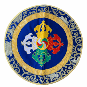 A round, blue altar placemat with golden trim and an embroidered double vajra design in the center, placed on a white background.