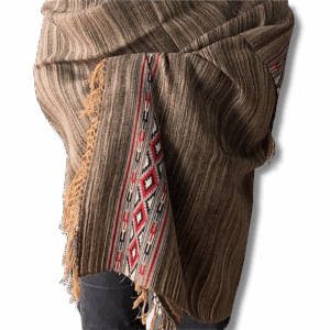 Handwoven black and caramel yak wool shawl draped over shoulders, featuring a traditional red, white and black patterned border and soft fringed edges.
