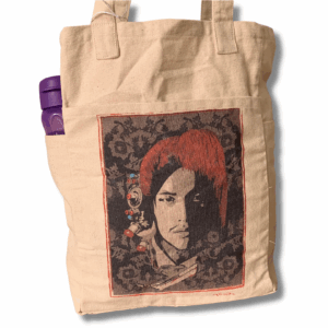 A beige tote bag featuring a central pocket with a printed Tibetan cultural art design, including a face with red hair and decorative elements.