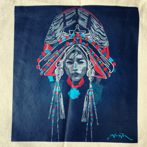 A navy blue tote bag featuring a central graphic of a Tibetan woman with a traditional headpiece, decorated with red and white accents and yaks.